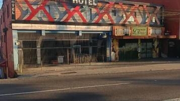 A hotel with a prominent sign, a gated entrance, and a red awning.