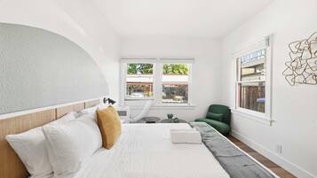 A modern bedroom with a bed, a green chair, and a view of the outside.
