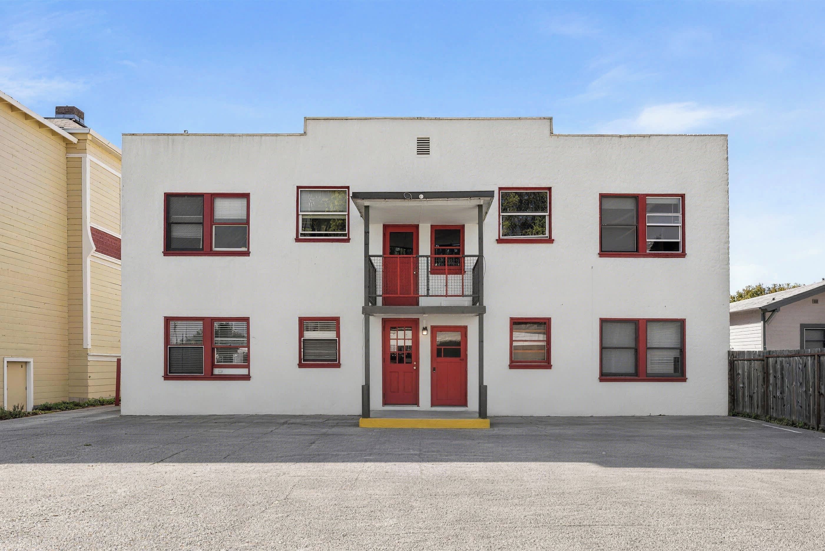 A two-story building with a central entrance, multiple windows, and a balcony.