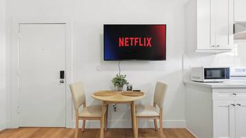 A modern kitchen with a flat-screen TV mounted on the wall displaying 'NETFLIX'.