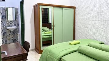Ein Schlafzimmer mit Bett, Kleiderschrank, Spiegel, Waschbecken und Wandverkleidung mit Muster.