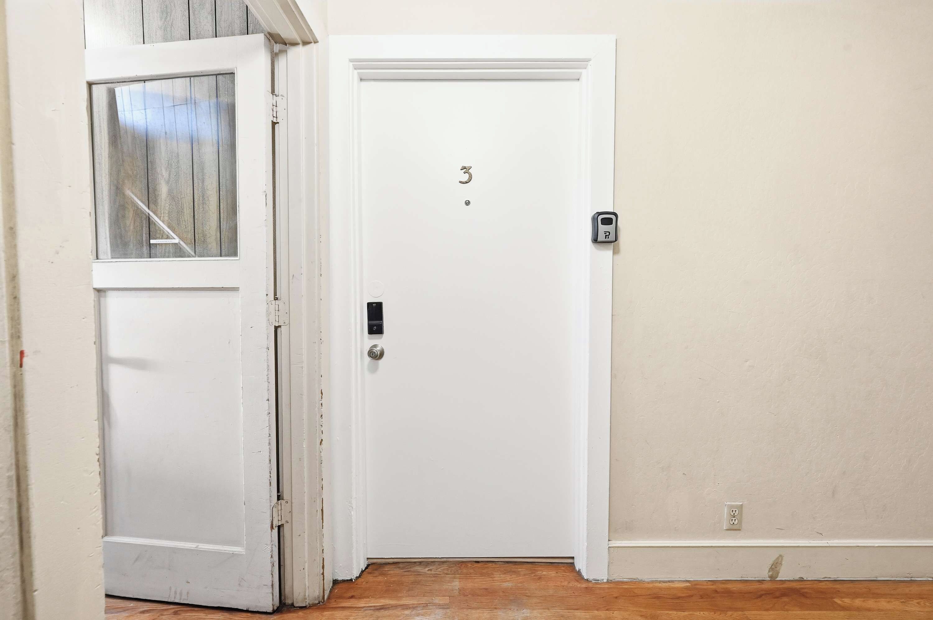 A white door with a number '3' on it, a keypad lock, and a small window above the door.