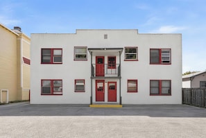 Un edificio de dos pisos con una entrada central, varias ventanas y un balcón.