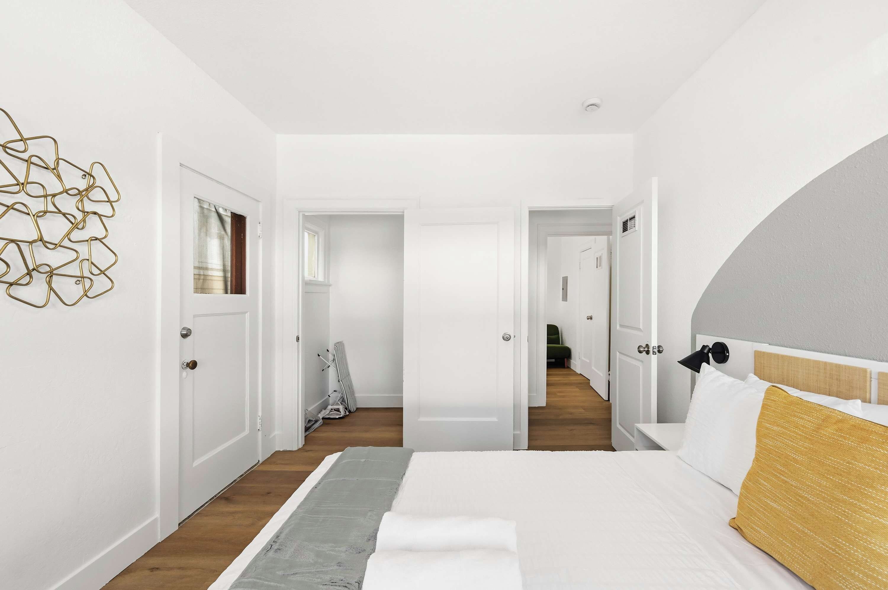 A modern bedroom with a large bed, a headboard, and a wall art piece.