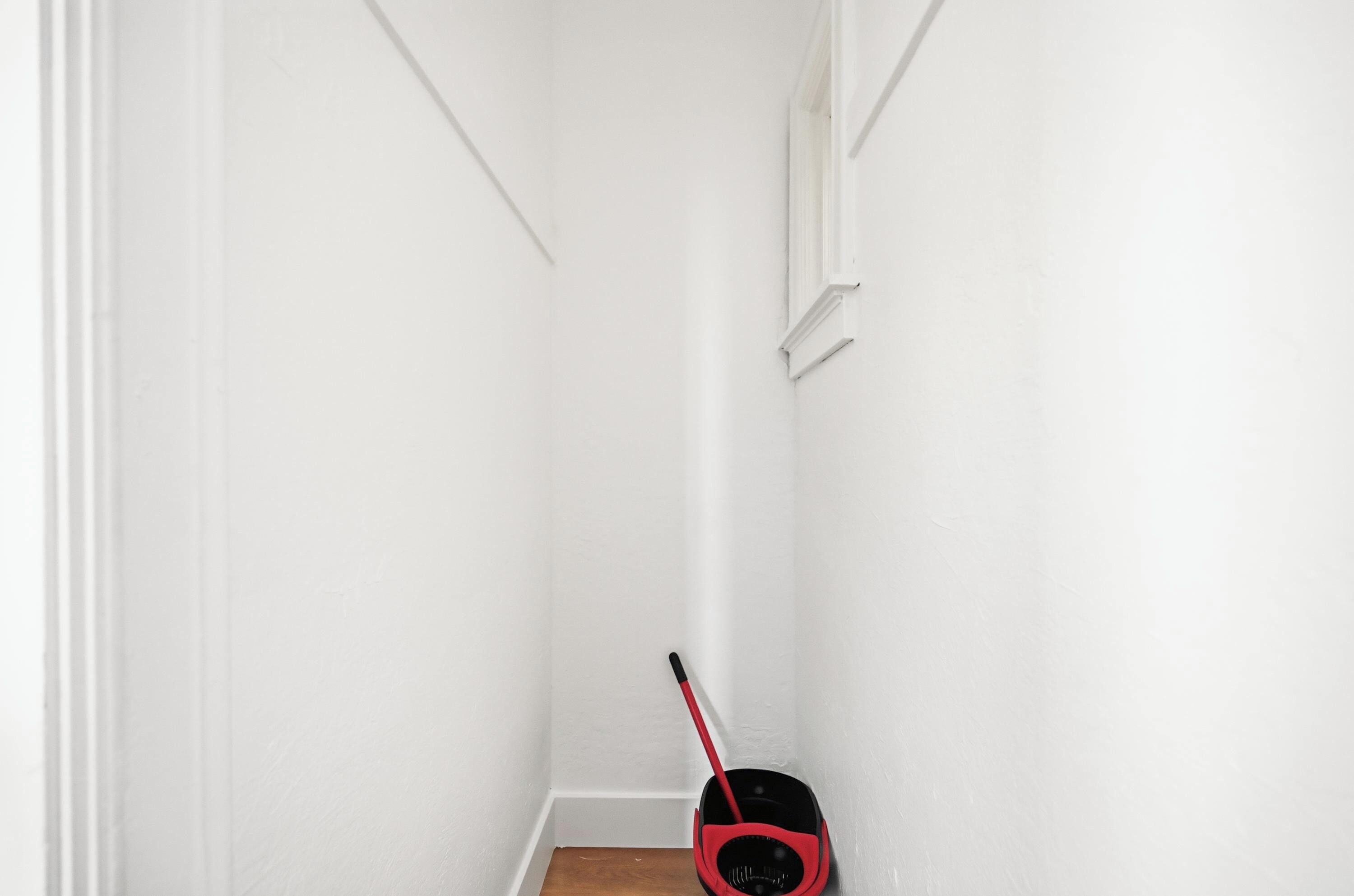 A narrow hallway with white walls and a wooden floor.