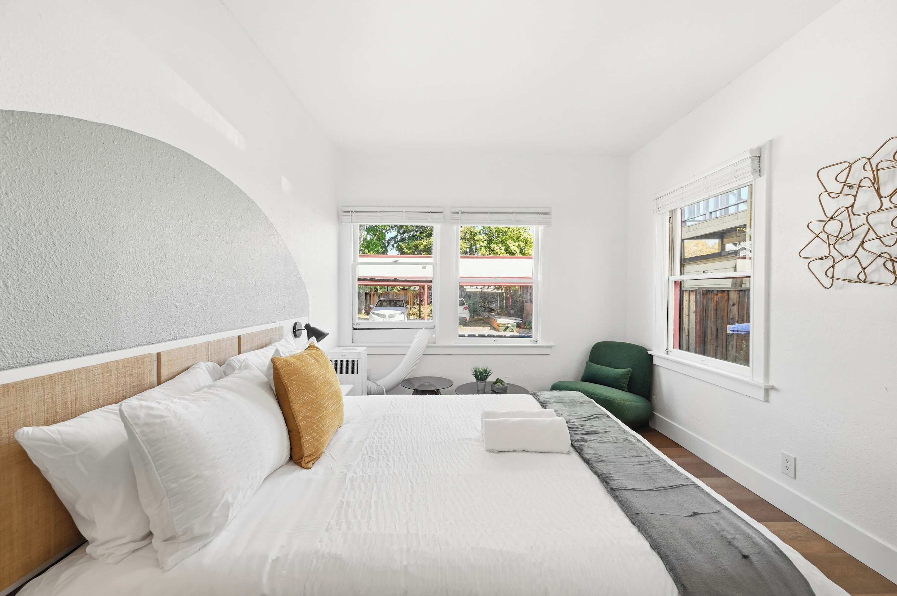 A modern bedroom with a bed, a green chair, and a view of the outside.