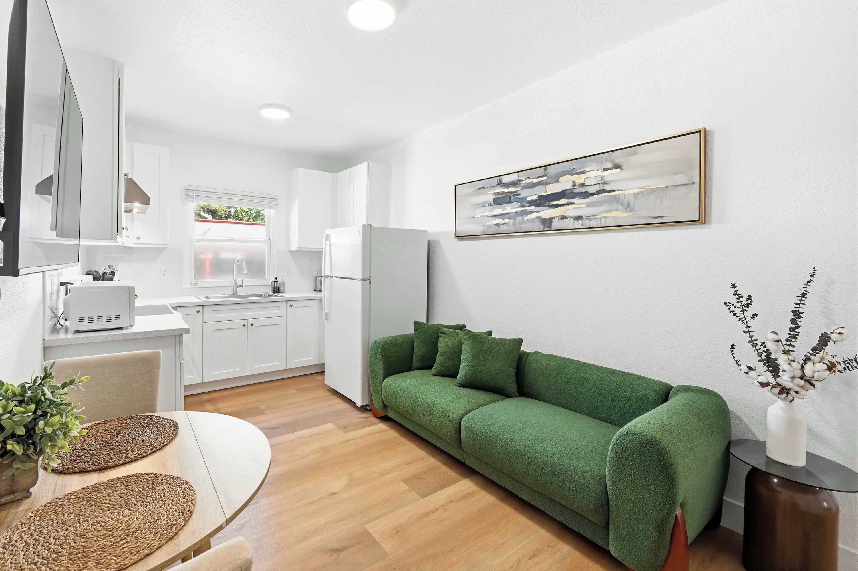 A modern kitchen with white cabinets, a built-in oven, and a window.