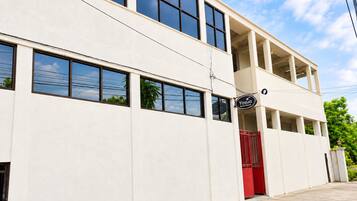 Um edifício de dois andares com fachada plana, janelas amplas e uma porta vermelha.