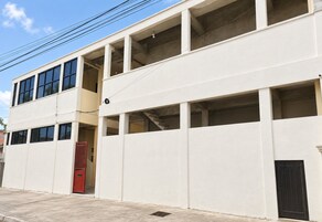 A two-story building with multiple windows and a red gate.