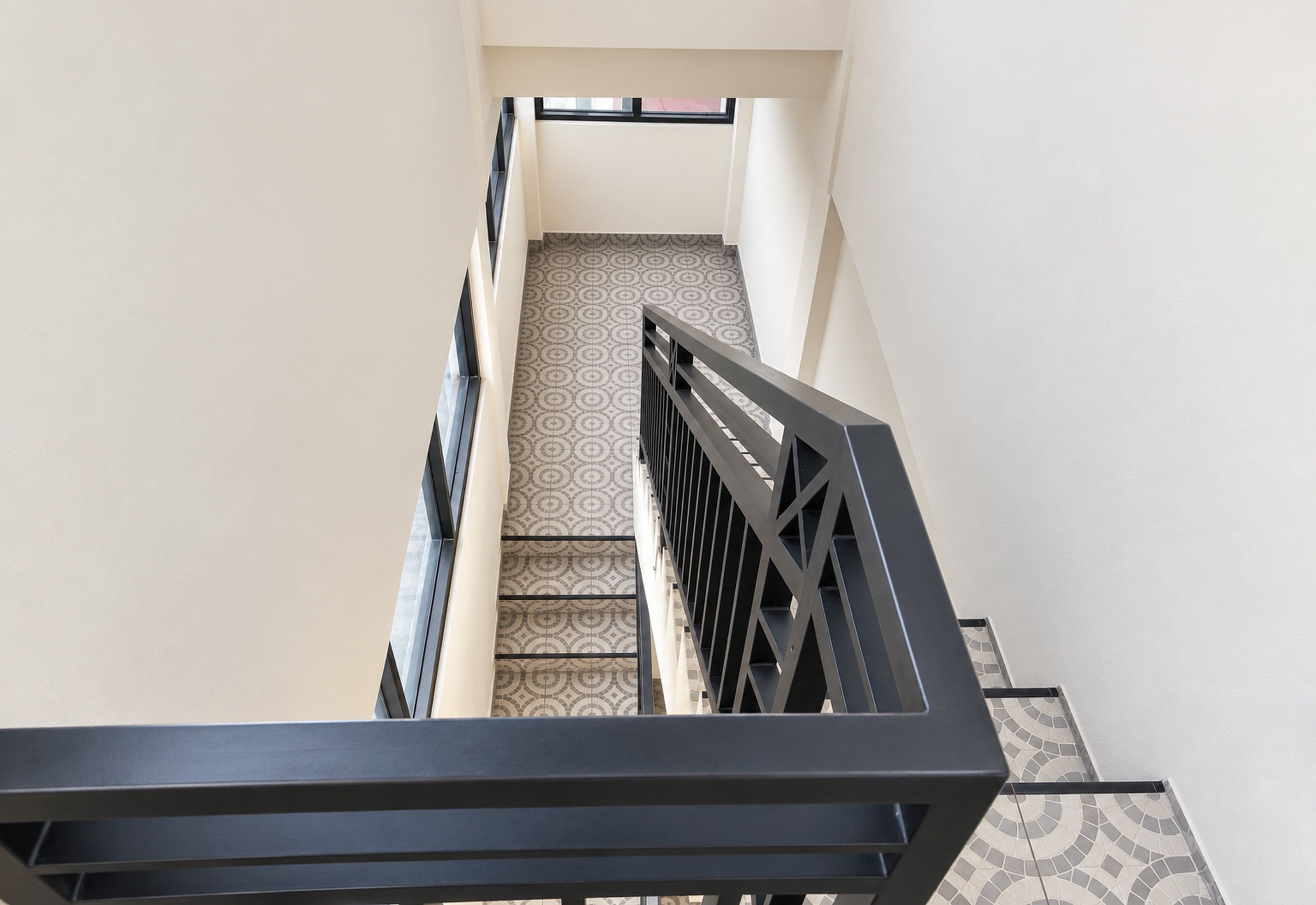 Un escalier doté d’un revêtement de sol à motifs et d’une rampe en métal.