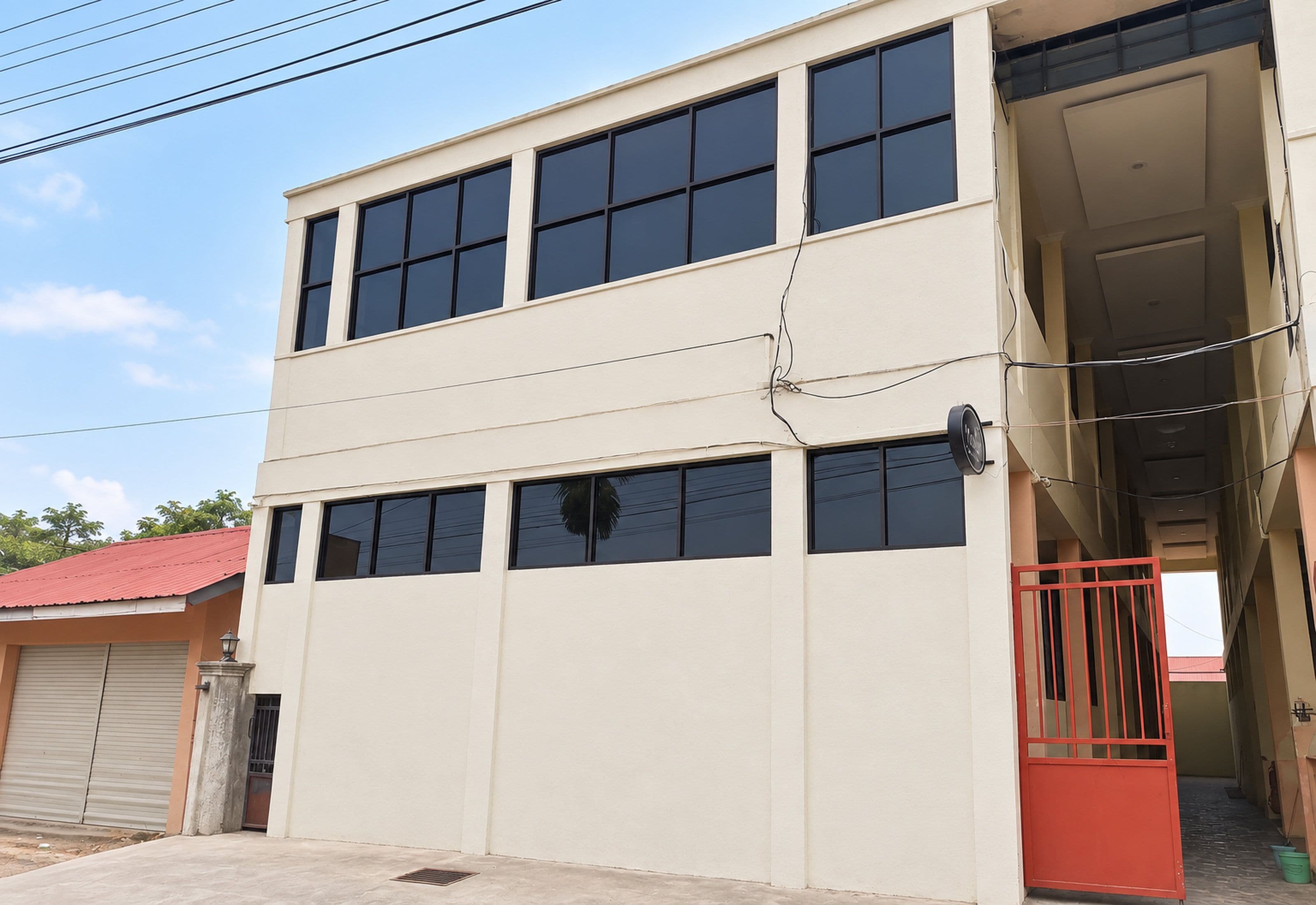 Un bâtiment à deux étages, doté de nombreuses fenêtres et d’un portail rouge.