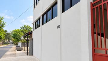 A modern building with a white facade, a red gate, and a clear sky.