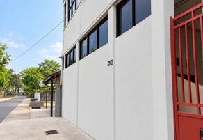 A modern building with a white facade, a red gate, and a clear sky.