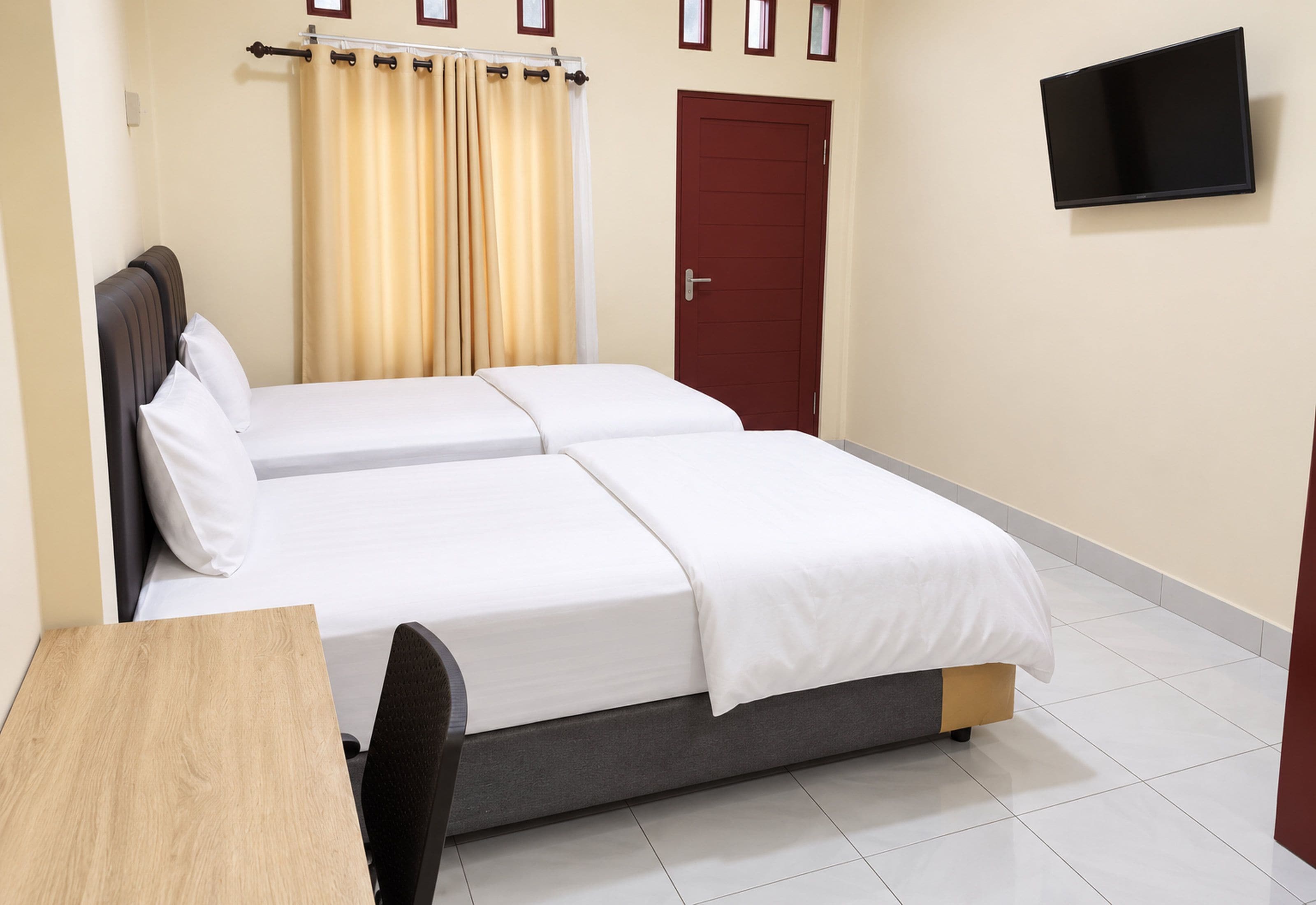Une chambre d’hôtel avec un lit, un téléviseur fixé au mur et une porte.