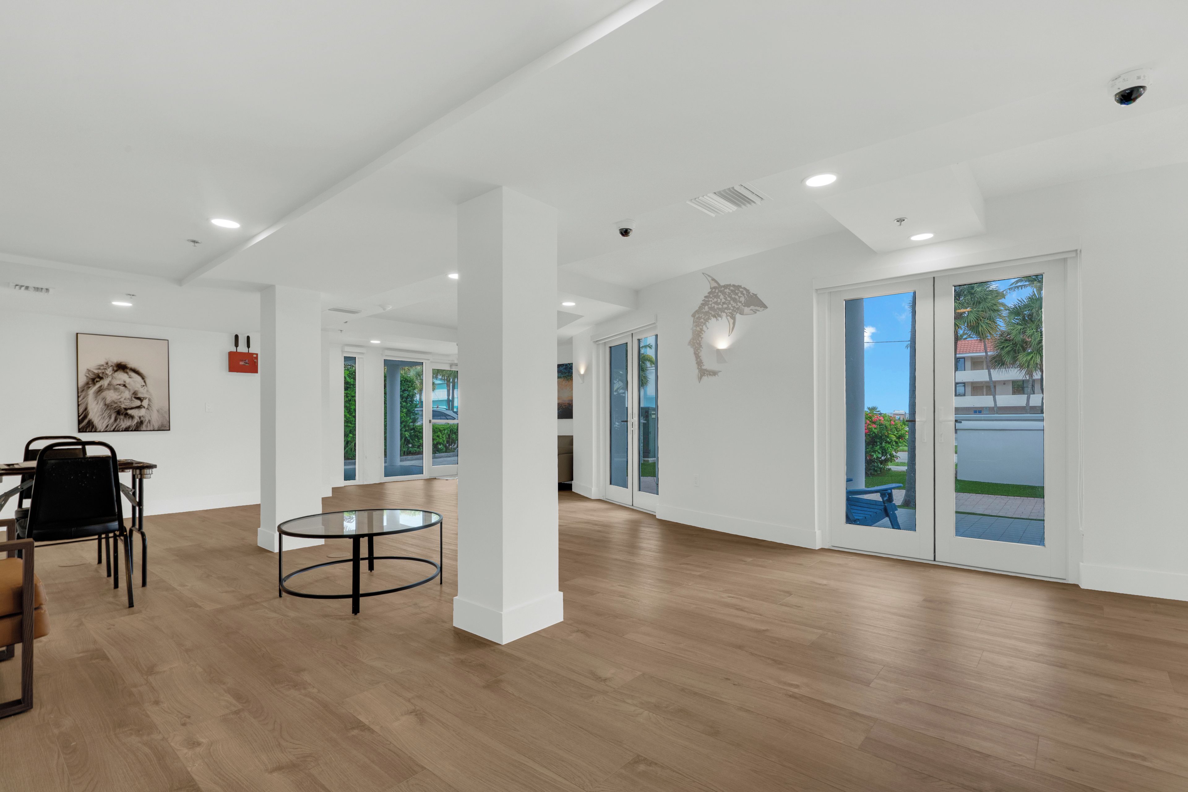 A spacious room with a wooden floor, a glass table, and a framed picture on the wall.