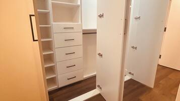Un armario con puerta abierta, suelo de madera y interior blanco.