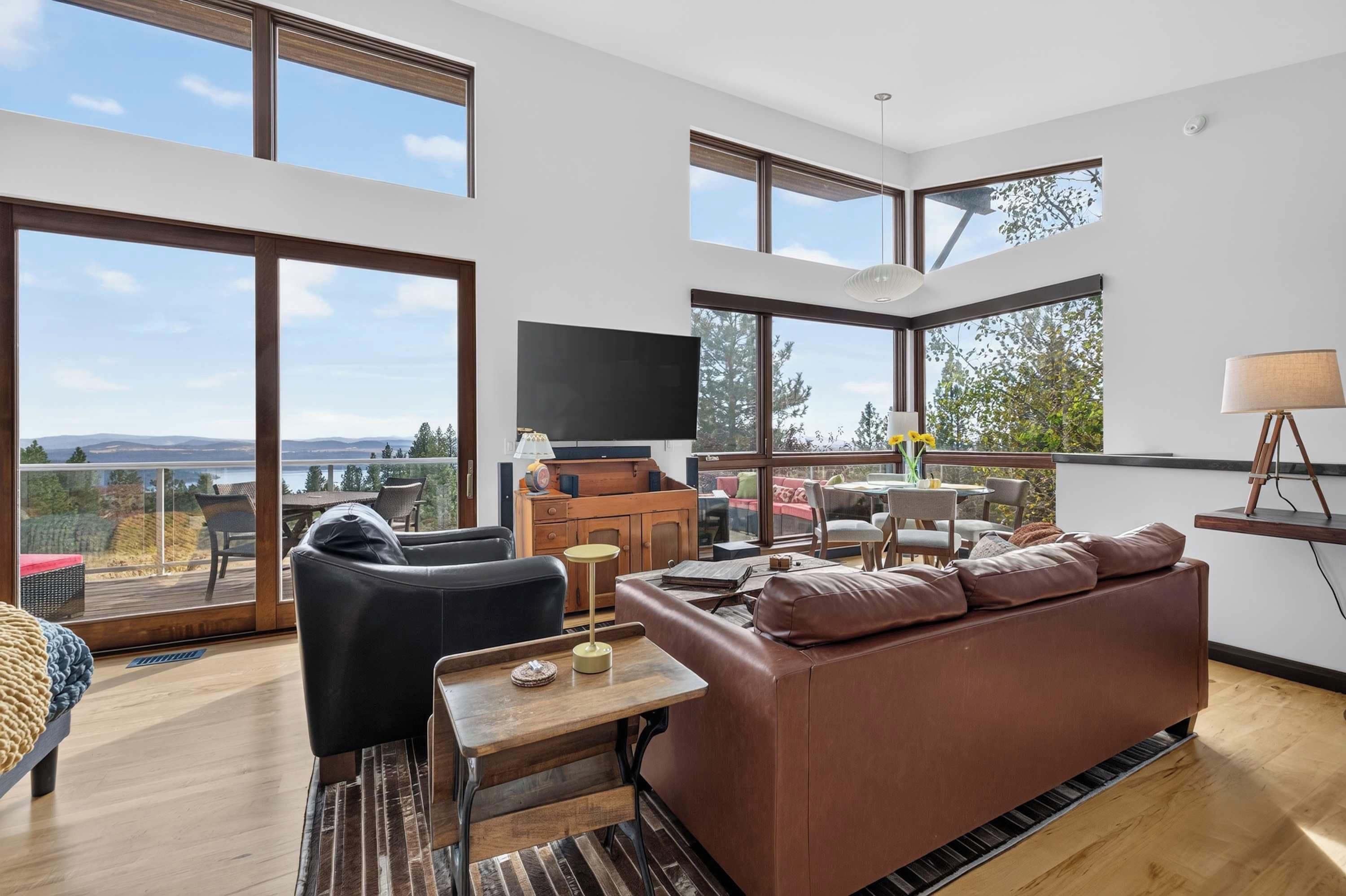 Un vaste espace de vie comprenant un grand canapé, une table basse et un téléviseur. Un balcon offre une vue sur le paysage.