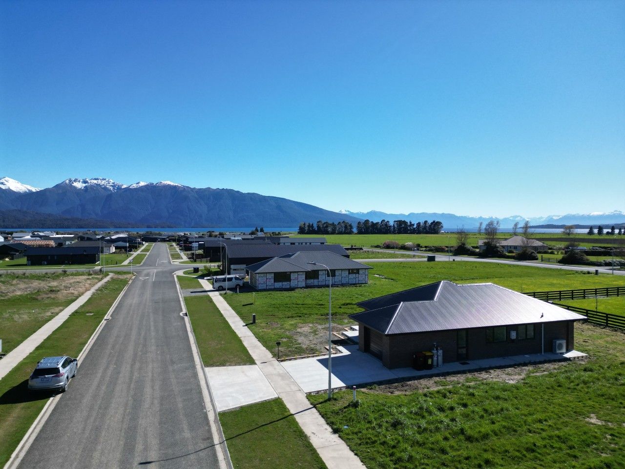 Un quartier résidentiel avec une route, des maisons et, au loin, une chaîne de montagnes.