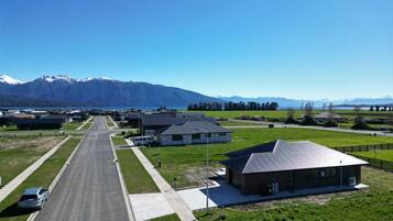 Un quartier résidentiel avec une route, des maisons et, au loin, une chaîne de montagnes.