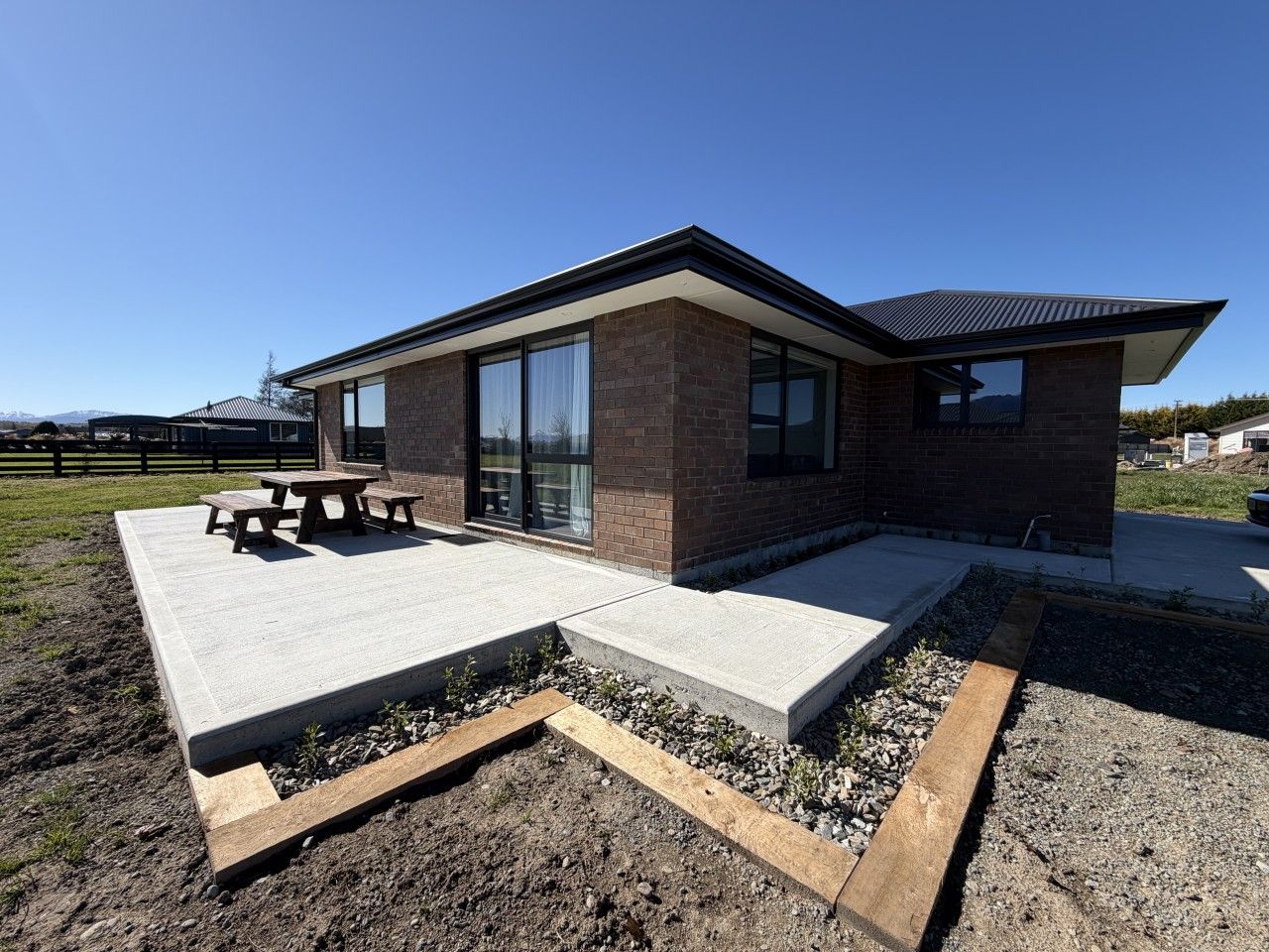 Un bâtiment moderne doté d’un patio, d’un espace extérieur aménagé pour s’asseoir et offrant une vue sur le paysage environnant.