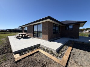 Ein modernes Gebäude mit einer Terrasse, Sitzgelegenheiten im Freien und Blick auf die umliegende Landschaft.