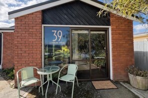 A building with a number '39' and the text 'LUXMORE DRIVE' on the front. There are two chairs and a table outside the entrance.