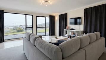 Ein modernes Wohnzimmer mit einem großen grauen Sofa, einem Flachbildfernseher und einem Bücherregal.
