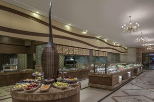 Zona de bufé con diversas opciones de comida, un columnilla decorativa y una pared con diseño.