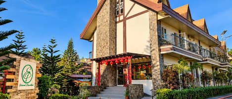 A hotel with a stone facade, multiple balconies, and a red lantern-adorned entrance.