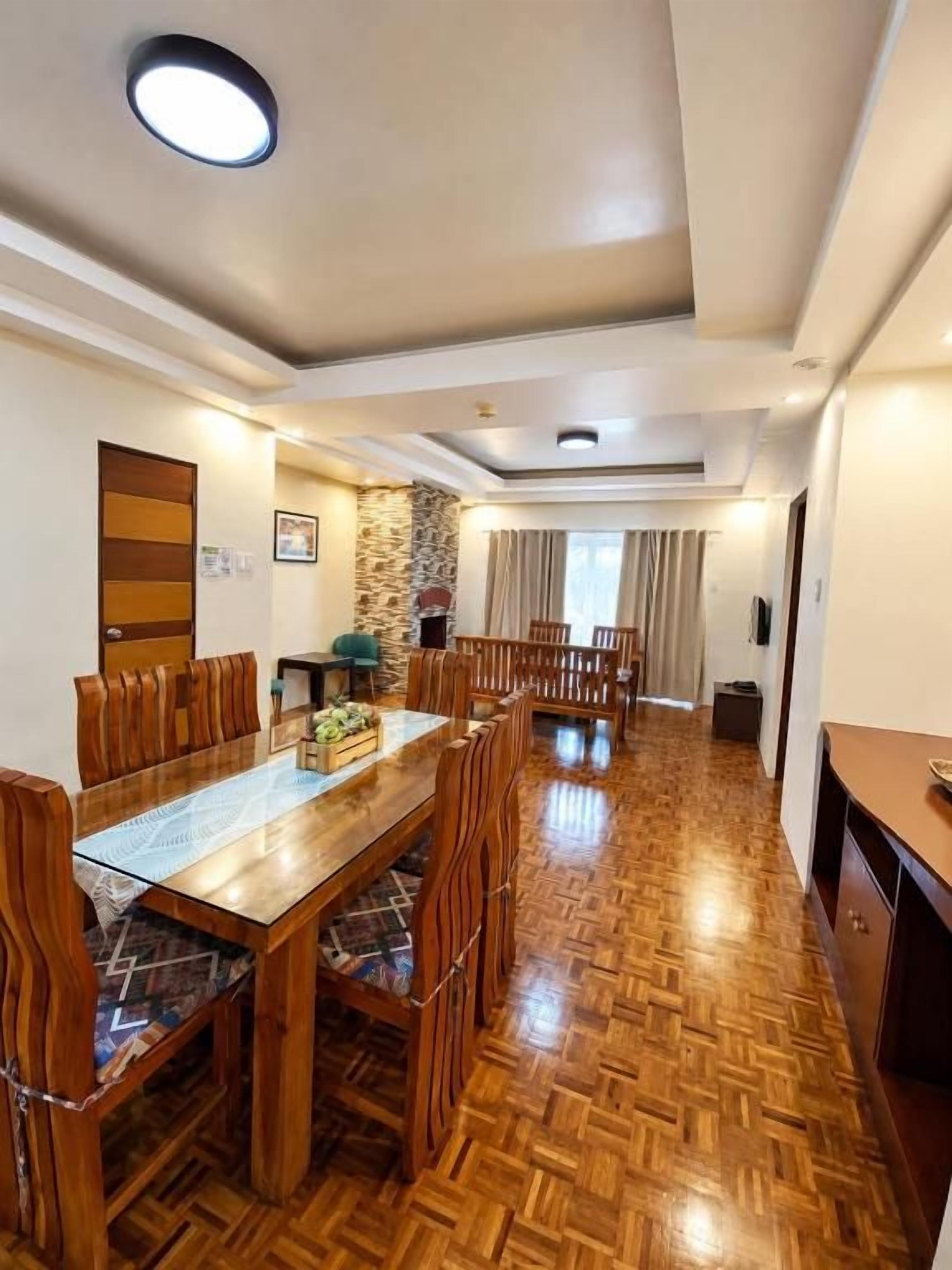 A spacious dining area with a wooden table and chairs, a stone accent wall, and a view into another room.
