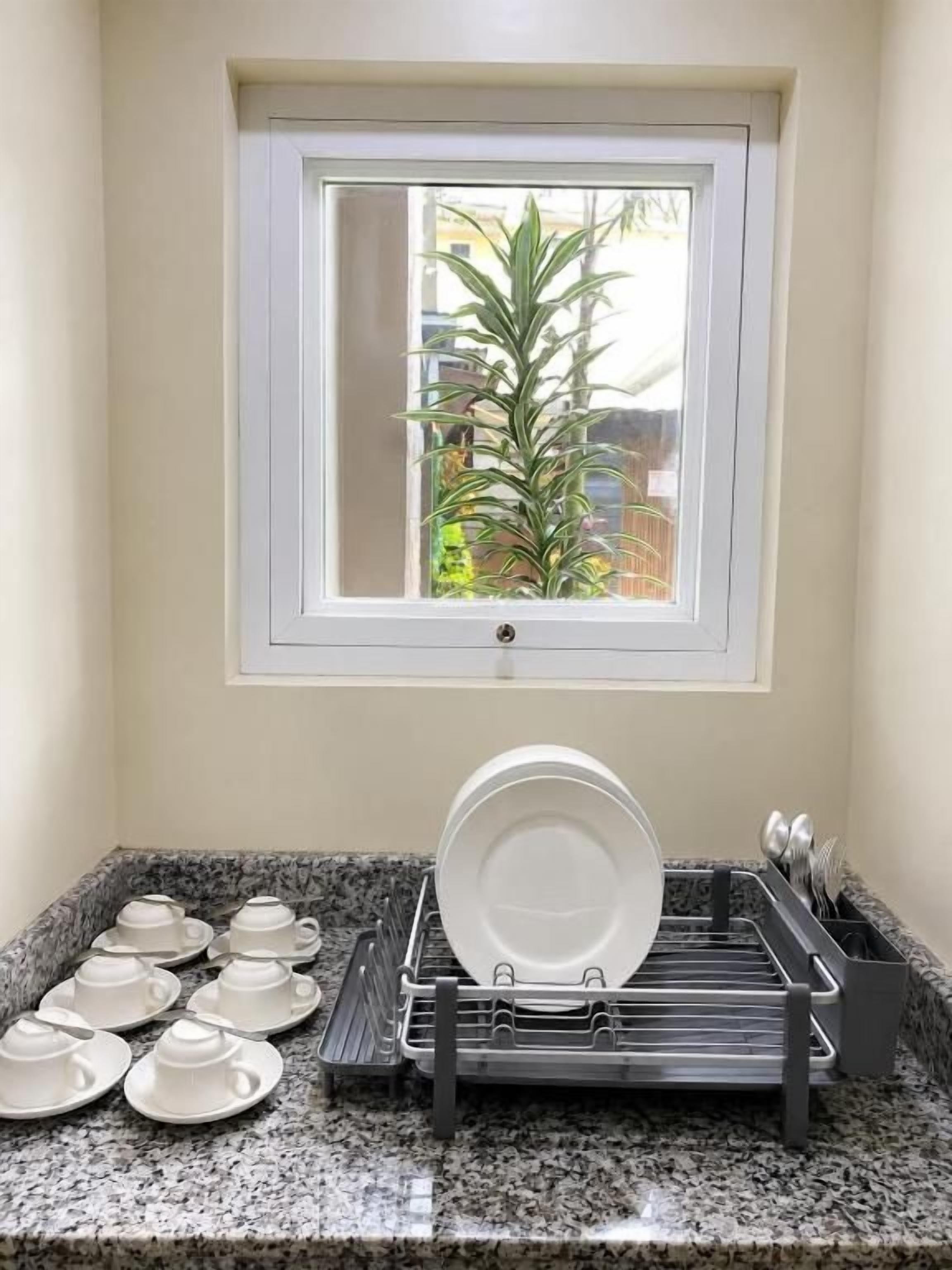 A kitchen with a window above a dish rack containing plates and bowls.