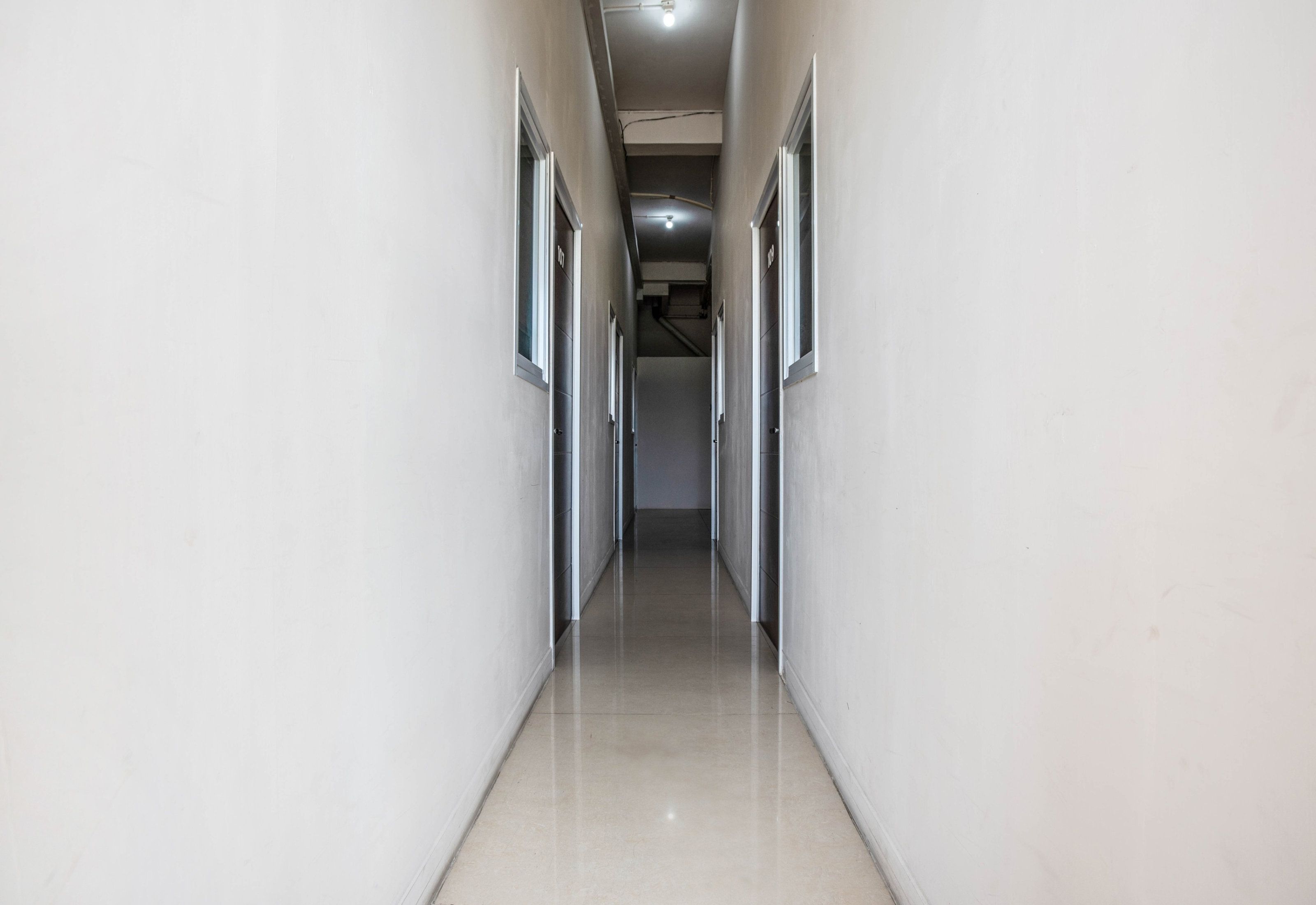 A corridor with doors on both sides, leading to an interior space.