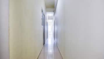 A long, narrow hallway with white walls and a shiny tiled floor.