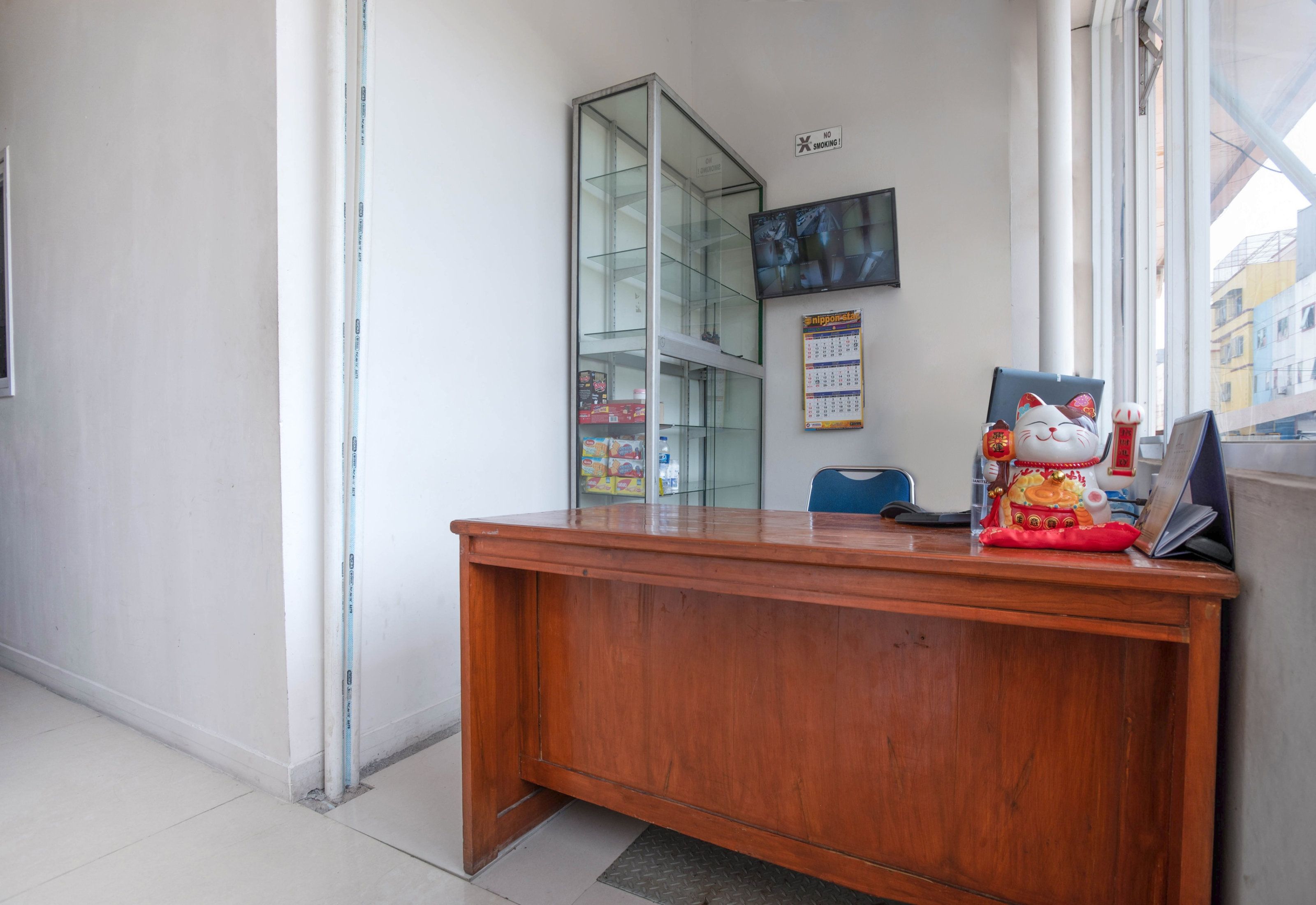 A wooden reception desk with a glass display cabinet, a calendar, and a cat figurine.