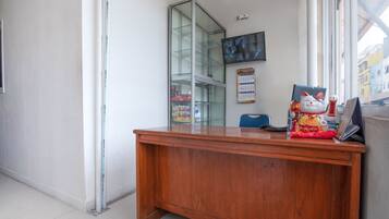 A wooden reception desk with a glass display cabinet, a calendar, and a cat figurine.