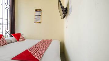 Habitación de hotel con cama, calendario, ventana con cortinas y aire acondicionado de pared.
