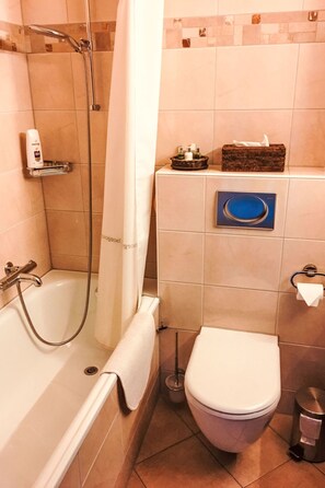 Een badkamer met een bad, toilet en douche.