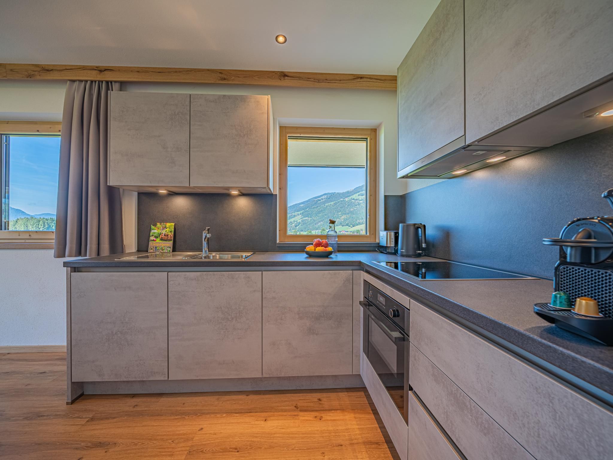 A modern kitchen with a built-in oven, a sink, and a window with a view of the outdoors.