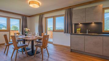 Eine moderne Küche mit Essbereich, Holzböden und großen Fenstern mit Blick ins Freie.