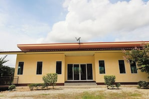 A two-story building with a flat roof, large windows, and a satellite dish.