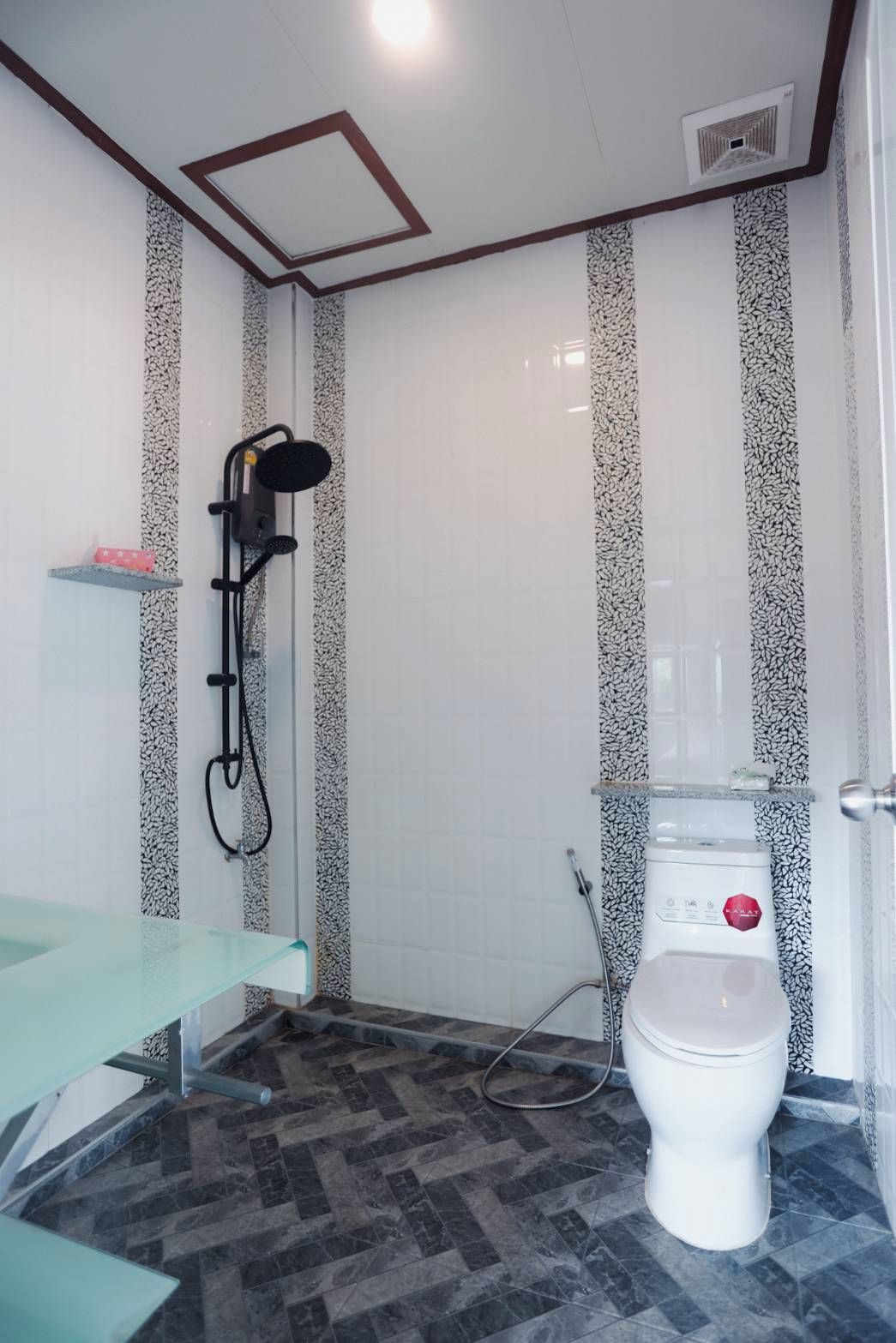 A bathroom with a shower, toilet, and a glass bench.