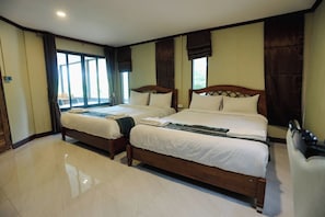 A hotel room with two wooden beds, a large window with curtains, and a tiled floor.