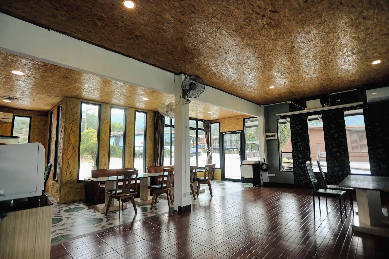 A spacious indoor area with a high ceiling, large windows, and a mix of seating arrangements.