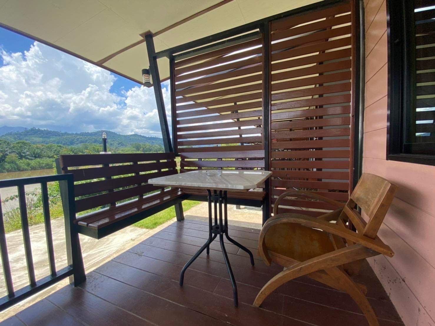 A covered outdoor seating area with a table and chairs, overlooking a scenic landscape.