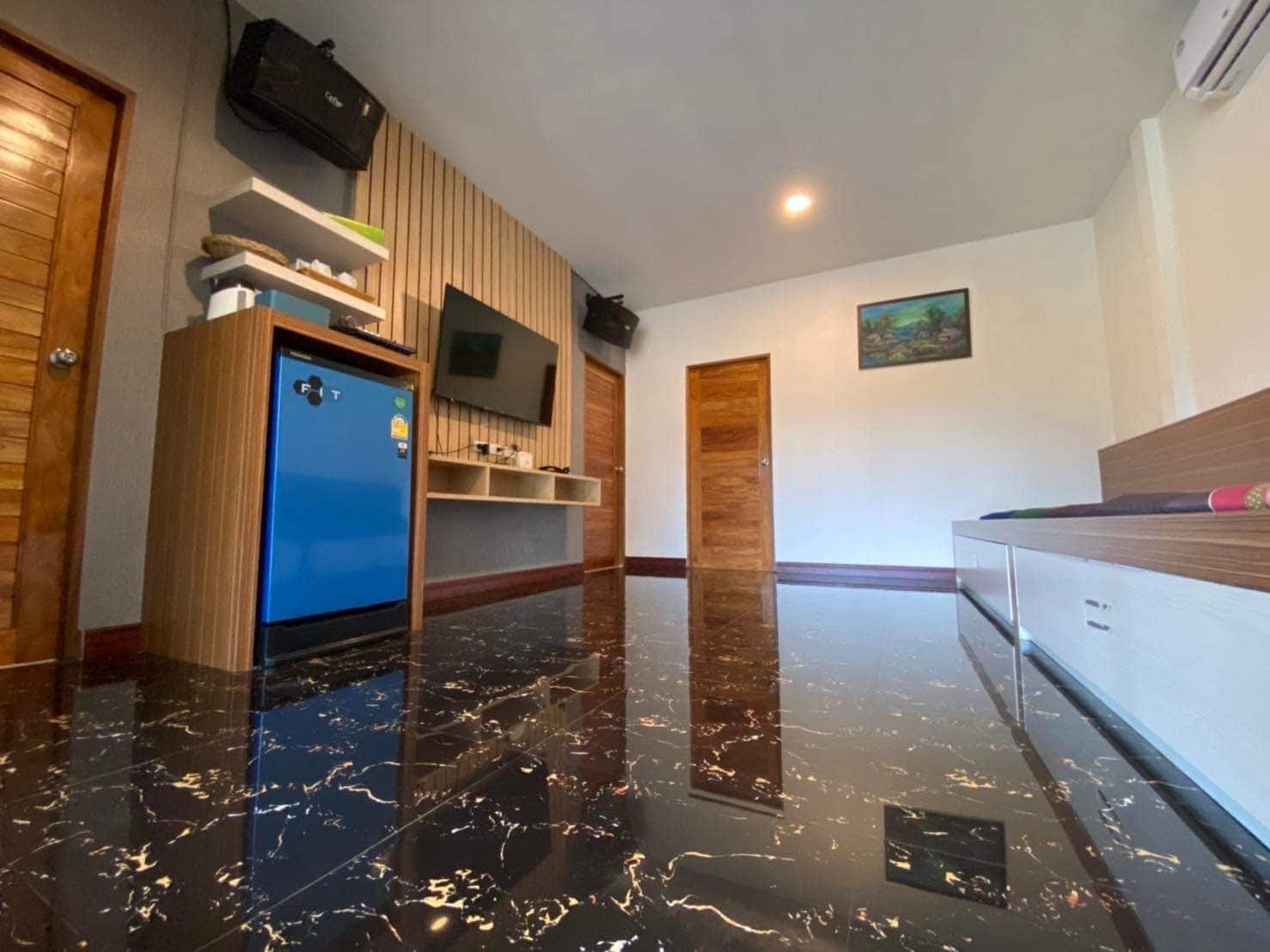 A modern kitchen with a blue refrigerator, wooden cabinets, and a flat-screen TV mounted on the wall.