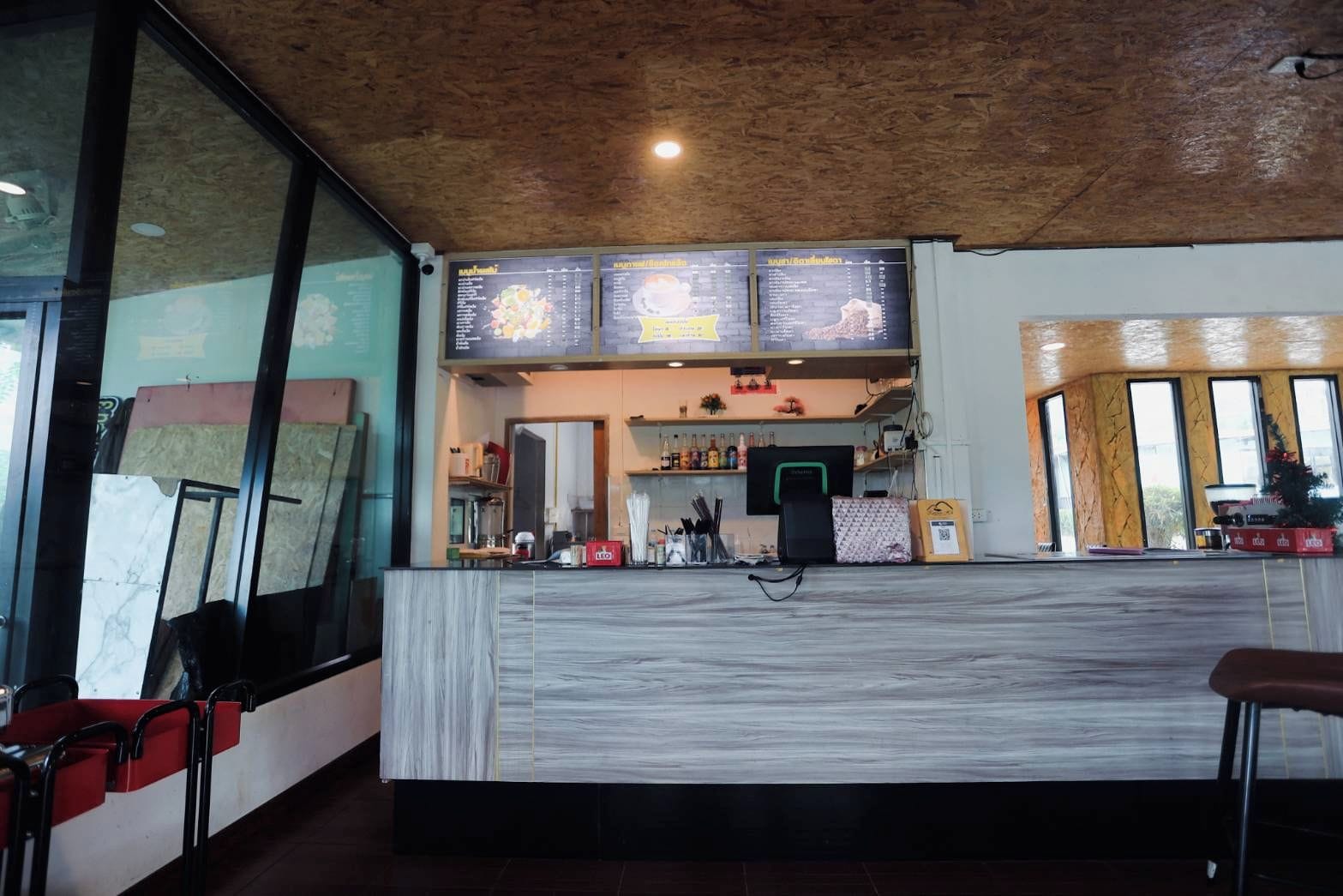 Un interior de restaurante con un mostrador de mármol, pizarras con la carta y vistas amplias a través de grandes ventanales.