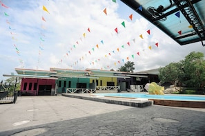 A building with a swimming pool, a covered area, and colorful flags.