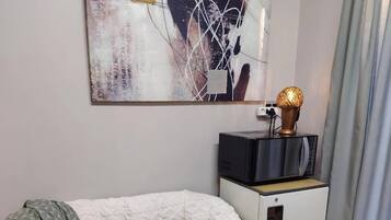 Une pièce confortable avec un canapé, une petite table, une lampe et un téléviseur posé sur un meuble.