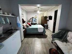A compact bedroom with a bed, a small desk, a chair, a wardrobe, and a television. - Cozy Granny Flat Near Cape Gate Hospital and Shopping Centre (Cape Town)