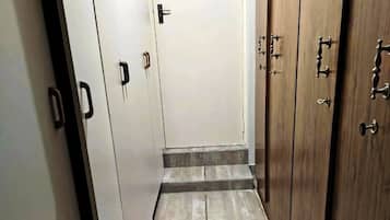 Un couloir étroit, avec une porte en bois au fond, bordé de meubles blancs dont les poignées sont noires.